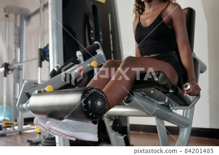 Woman Exercising on Leg Extension Machine Woman Exercising on Leg Extension Machine 84201485