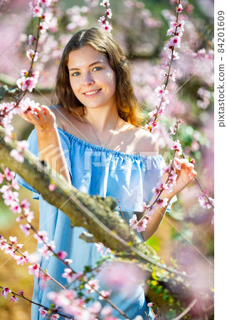 Portrait of young smiling woman in a garden with blooming peach Portrait of young smiling woman in a garden with blooming peach 84201609