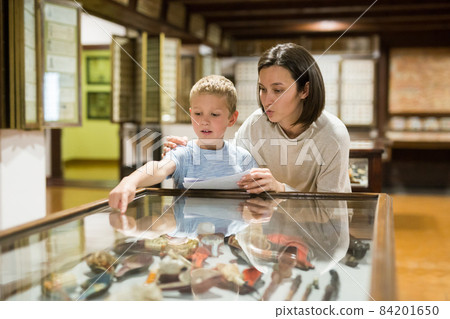 Woman and boy exploring artworks in museum 84201650