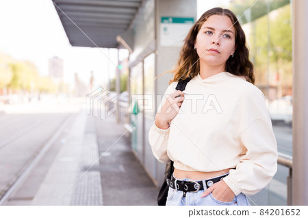 Portrait of a girl standing at a stop waiting for transport 84201652