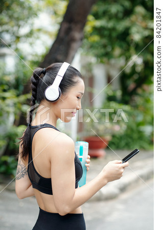 Jogger in Headphones Turning on Music Jogger in Headphones Turning on Music 84201847
