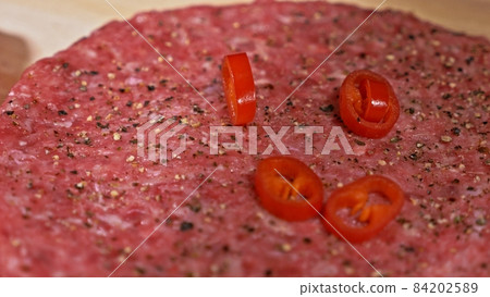 Cook makes meat medallions for burgers. Chef in black food gloves makes cutlet. Cutlets are leveled in steel ring in an even medallion. 84202589