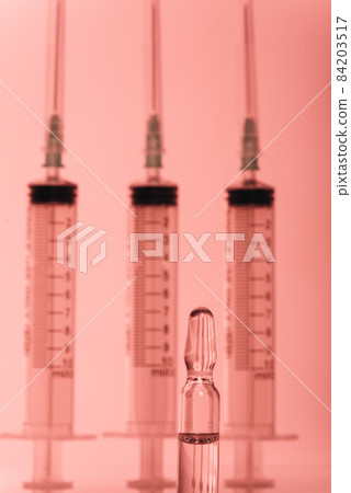 Glass medical ampoule vial for injection. Medicine is liquid sodium chloride with of aqueous solution in ampulla. Close up. Bottles ampule multicolor. 84203517