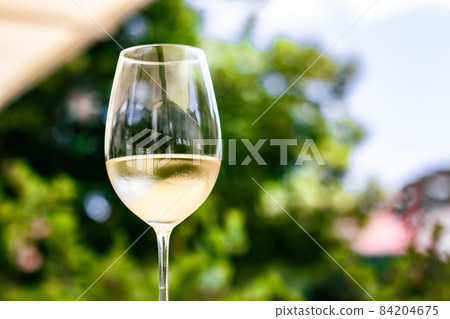 White wine in luxury restaurant on summer garden terrace, wine tasting experience at winery in the vineyard, gourmet tour and holiday travel White wine in luxury restaurant on summer garden terrace, wine tasting experience at winery in the vineyard, gourmet tour and holiday travel 84204675
