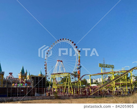 Ferris wheel and roller coaster rides at pier pacific park at sunset with people riding attractions 84205905