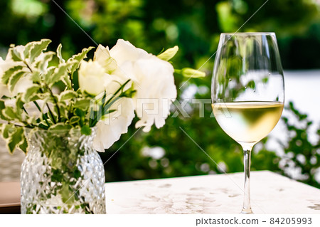 White wine in luxury restaurant on summer garden terrace, wine tasting experience at winery in the vineyard, gourmet tour and holiday travel White wine in luxury restaurant on summer garden terrace, wine tasting experience at winery in the vineyard, gourmet tour and holiday travel 84205993