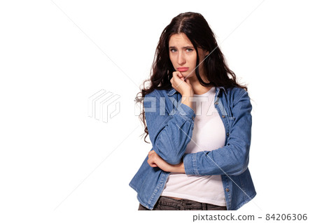 Beautiful and unhappy young woman with dark wavy hair looking into the camera with serious expression on her face. Beautiful and unhappy young woman with dark wavy hair looking into the camera with serious expression on her face. 84206306