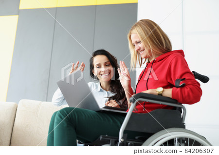 Sisters waving hello to family via online video call using laptop 84206307