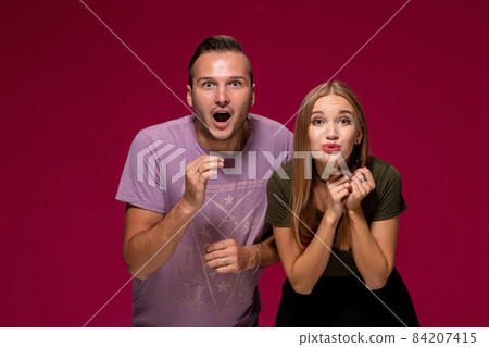 Girlfriend decided with her cute boyfriend to buy puppy. Indoor studio shot on burgundy background. 84207415