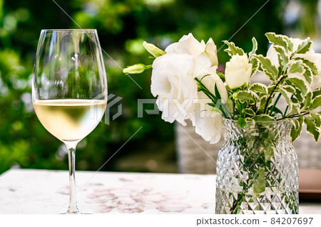 White wine in luxury restaurant on summer garden terrace, wine tasting experience at winery in the vineyard, gourmet tour and holiday travel White wine in luxury restaurant on summer garden terrace, wine tasting experience at winery in the vineyard, gourmet tour and holiday travel 84207697