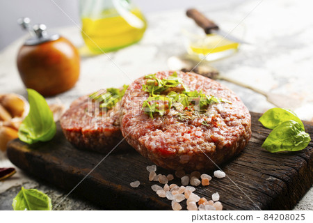 Raw cutlet of minced meat on a wooden cutting board. 84208025
