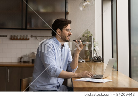 Concentrated young businessman recording audio message. 84209448