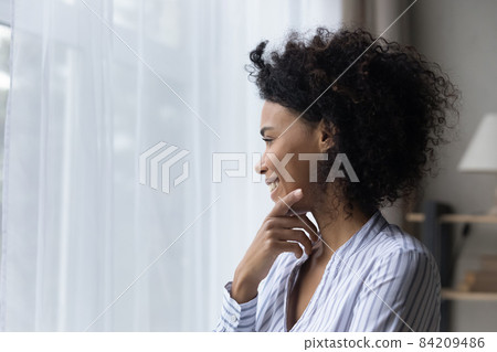 Head shot smiling dreamy African American woman looking at window 84209486