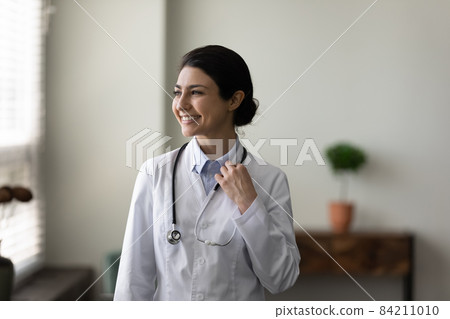 Head shot dreamy smiling Indian female doctor looking in distance 84211010