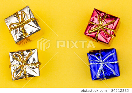 Box with gift on a yellow background with copy space for text. Golden, red, blue boxes with gifts. Christmas gift boxes. Holidays Gifting. New Year gift boxes to family woman, man. Top view. Close-up 84212283