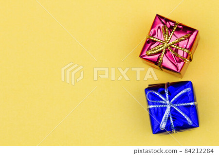 Box with gift on a yellow background with copy space for text. Red and blue boxes with gifts. Christmas gift boxes. Holidays Gifting. New Year gift boxes to family woman, man. Top view. Close-up 84212284