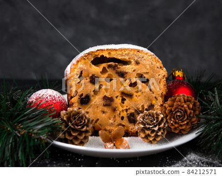 Christmas fruitcake powdered sugar on white plate dark background seasonal decorations. Xmas atmospheric greeting card. Christmas fruitcake powdered sugar on white plate dark background seasonal decorations. Xmas atmospheric greeting card. 84212571