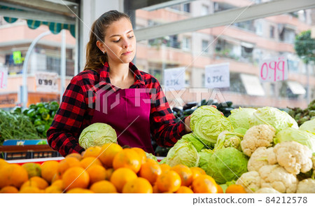 Focused girl of the seller lays out cabbages on the counter 84212578