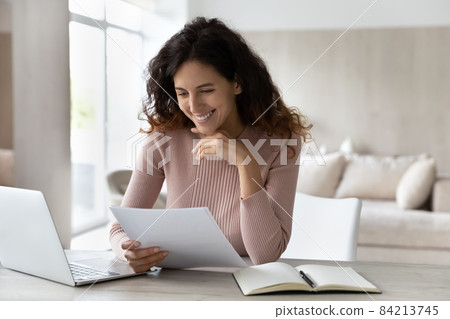 Happy businesswoman reading good news in letter, sitting at desk 84213745