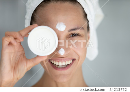 Happy millennial latin hispanic woman applying cream on face. Happy millennial latin hispanic woman applying cream on face. 84213752