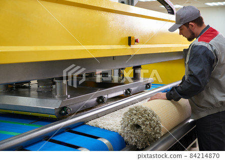 Laundry worker in the process of working on automatic machine for carpet washing in dry cleaning 84214870