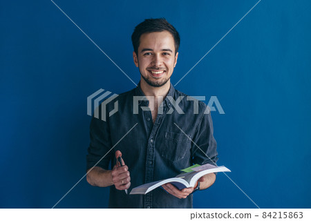 Male student. Man standing over dark blue background looking camera 84215863