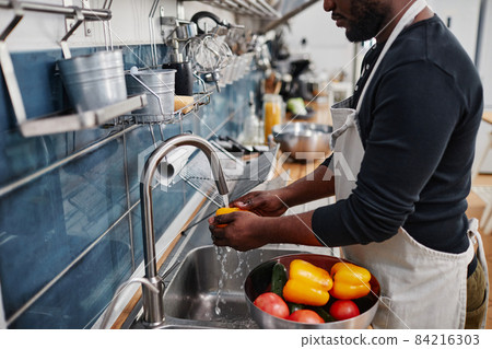 Man Washing Vegetables in Sink Man Washing Vegetables in Sink 84216303