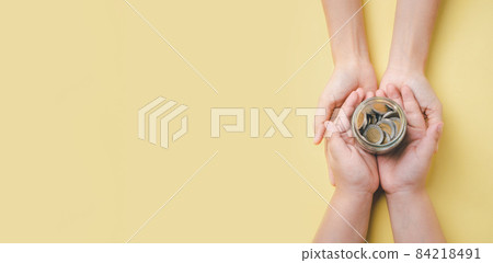 Mother and son hand holding money in glass jar on yellow background, donation, saving, charity, family finance plan concept, fundrasing community care, superannuation, financial crisis concept Mother and son hand holding money in glass jar on yellow background, donation, saving, charity, family finance plan concept, fundrasing community care, superannuation, financial crisis concept 84218491