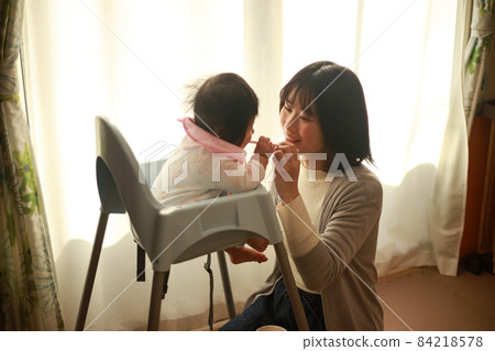 Mother giving a baby food to a baby Mother giving a baby food to a baby 84218578