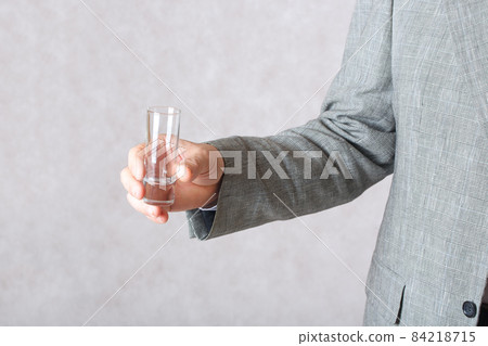 A small glass in the hand of a man A small glass in the hand of a man 84218715