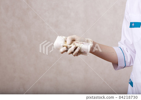 A young woman dressed in a medical uniform keeps money A young woman dressed in a medical uniform keeps money 84218730