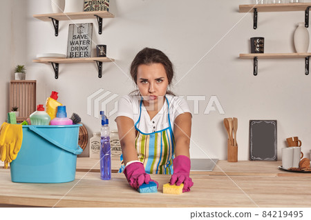 Beautiful cheerful brunette woman in gloves cleaning modern kitchen Beautiful cheerful brunette woman in gloves cleaning modern kitchen 84219495