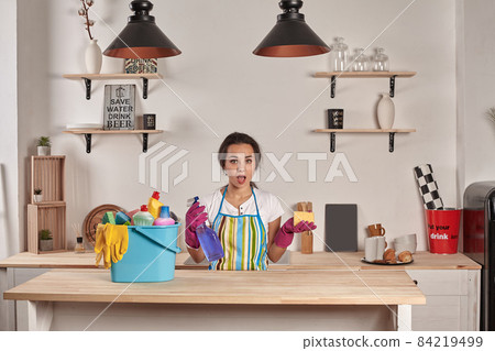 Beautiful cheerful brunette woman in gloves cleaning modern kitchen 84219499