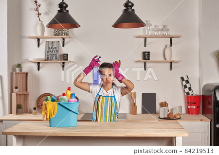 Woman wearing gloves, holding with a sponge in his hands, bowl full of bottles with disinfectant on table Woman wearing gloves, holding with a sponge in his hands, bowl full of bottles with disinfectant on table 84219513