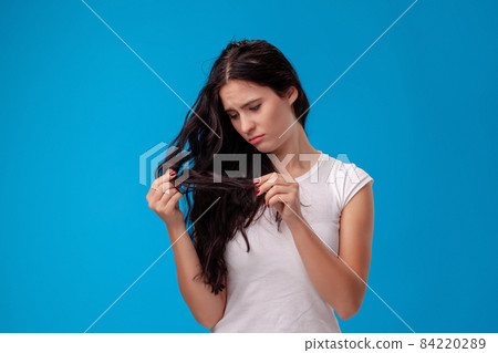 Sad woman is pulling her hair on blue background 84220289