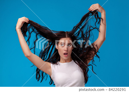 Surprised woman is pulling her hair and looking away Surprised woman is pulling her hair and looking away 84220291