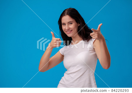 Smiling woman giving thumbs up on blue background Smiling woman giving thumbs up on blue background 84220293