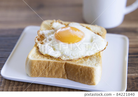 Delicious fried egg topped with thick sliced bread toast and hot coffee 84221840