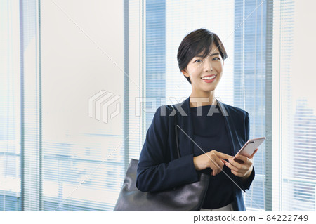 Business woman looking at a smartphone in the office Business woman looking at a smartphone in the office 84222749