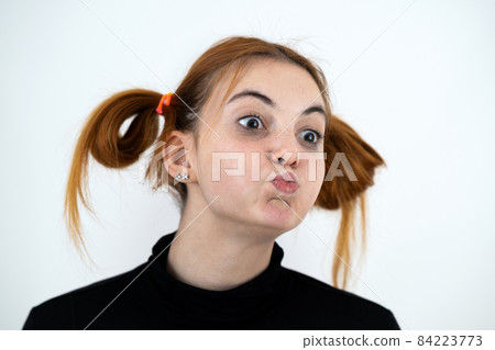 Closeup portrait of a funny redhead teenage girl with childish hairstyle isolated on white backround. 84223773