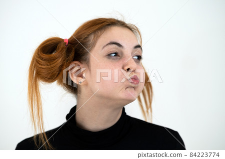 Closeup portrait of a funny redhead teenage girl with childish hairstyle isolated on white backround. 84223774