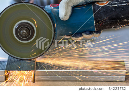 Close-up of worker cutting metal with grinder. Sparks while grinding iron. Close-up of worker cutting metal with grinder. Sparks while grinding iron. 84223782