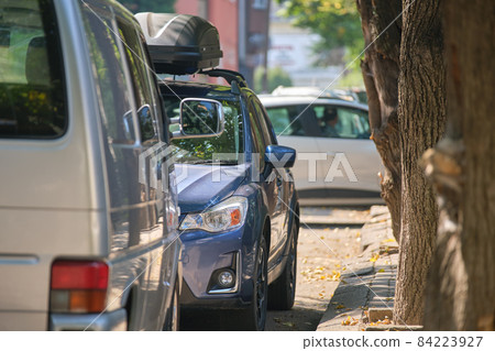 City traffic with cars parked in line on street side. 84223927