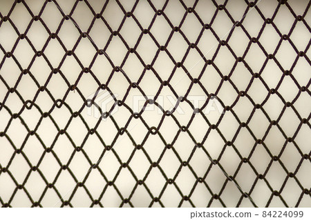 Background and texture for design. Abstract chain link fence texture against grungy gray color wall. 84224099
