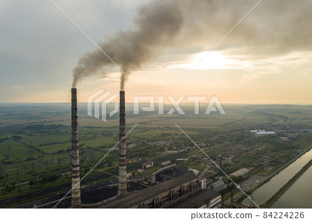 Aerial view of high chimney pipes with grey smoke from coal power plant. Production of electricity with fossil fuel. 84224226
