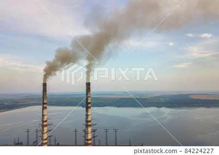 Aerial view of high chimney pipes with grey smoke from coal power plant. Production of electricity with fossil fuel. 84224227