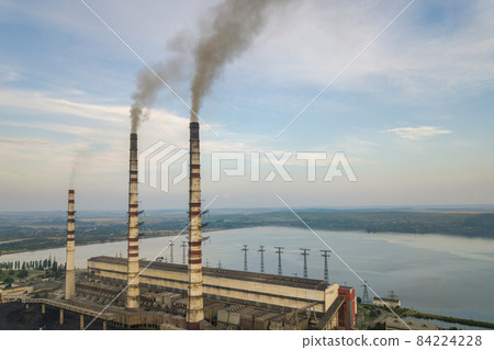 Aerial view of high chimney pipes with grey smoke from coal power plant. Production of electricity with fossil fuel. 84224228