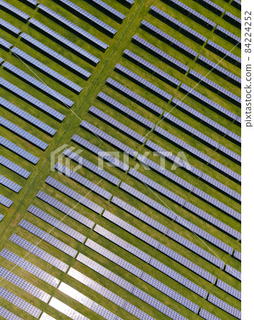 Aerial view of big sustainable electric power plant with many rows of solar photovoltaic panels for producing clean ecological electrical energy. Renewable electricity with zero emission concept. Aerial view of big sustainable electric power plant with many rows of solar photovoltaic panels for producing clean ecological electrical energy. Renewable electricity with zero emission concept. 84224252