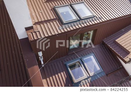 Aerial view of annex room exterior with plastic attic windows, roof and walls covered with brown metal decorative siding planks. Aerial view of annex room exterior with plastic attic windows, roof and walls covered with brown metal decorative siding planks. 84224255