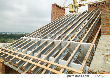 Stainless steel roof structure for future roof under construction. Development of metal roofing frame on house top. Stainless steel roof structure for future roof under construction. Development of metal roofing frame on house top. 84224632